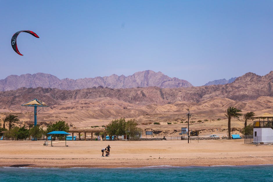 pexels photo 17472770 17472770 Áqaba beach scene with kite surfing and distant mountains, capturing a sunny, wind-filled day.